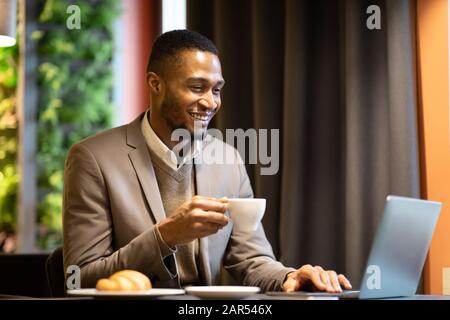 Afro manager drinking tea and using pc Stock Photo