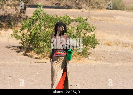 A Afar woman with a child on her back covers her face, Afar Region, Ethiopia.T he ancestors of the Afar settled farm land in the Ethiopian highlands s Stock Photo