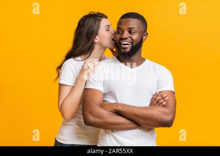 Romantic woman whispering about love into her black boyfriend's ear