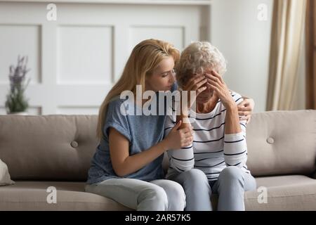 Worrying blonde young woman calming frustrated middle aged mommy. Stock Photo