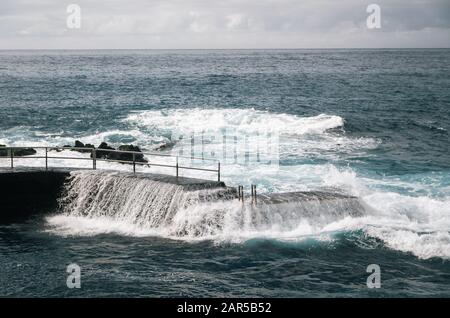 Wild Waves at rock pool. Entrance to Atlantic ocean with handrail in Puerto de la Cruz, Tenerife, Canary islands, Spain Stock Photo