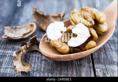Walnuts and walnut kernels lie in a spoon on a rustic old wooden table. Kernels of walnuts. Harvest walnuts. Stock Photo
