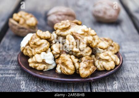Walnut kernels lie in a bowl on a rustic old wooden table. Fresh walnuts. Harvest walnuts. Stock Photo