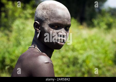 Portrait of young Mursi warrior. The Mursi (or Murzu) are a Sub-Saharan African nomadic cattle herder tribe located in the Omo valley in southwestern Stock Photo