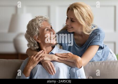 Smiling middle aged pleasant woman looking at attractive grownup daughter. Stock Photo