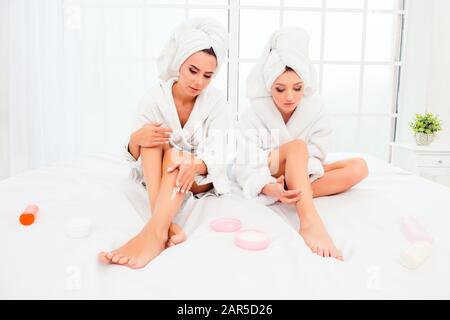 Nice young women smearing their legs with cream Stock Photo