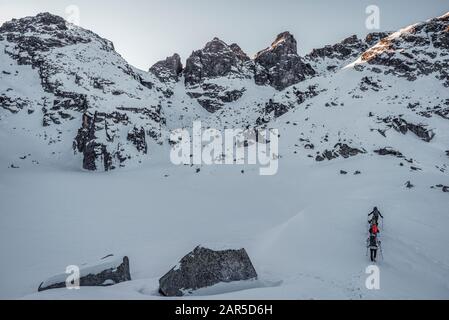 Group of hikers. Frozen Scary lake in front of Kupens peaks in Rila mountain national park, Malyovitsa region, Bulgaria Stock Photo