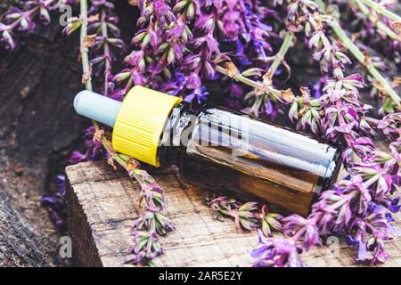 Lavender essential oil in a glass bottle and lavender colors on a rustic wooden background. Tincture or essential oil with lavender. Spa herbal medici Stock Photo