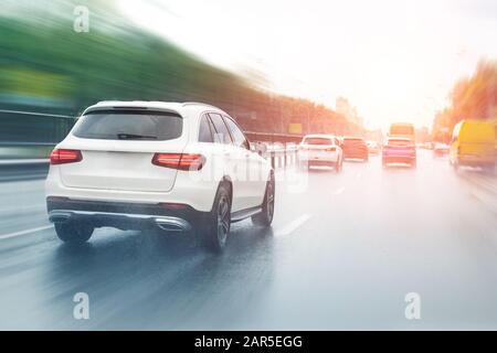 Wet highway after heavy rain with warm sunset evening sun on background. Vehicles riding with high speed by rainy city street road. aquaplaning or Stock Photo