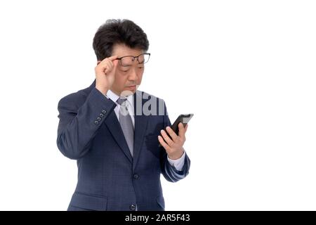 Asian businessman trying to read something on his mobile phone. poor sight, presbyopia, myopia. Stock Photo