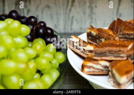 close-up of the edges of two plates standing on the distribution in the hotel's dining room. Sliced pie on one plate and grapes on another Stock Photo