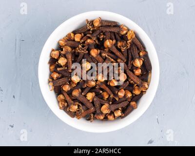 Cloves spice in a white bowl on a gray concrete background Stock Photo