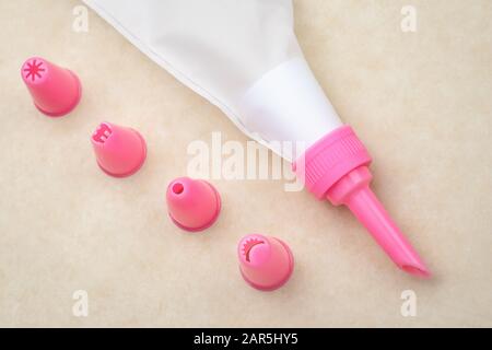 The pastry bag with pink nozzles on neutral paper background for cake decoration Stock Photo