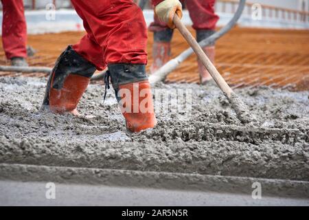 Group of construction workers spreading freshly poured concrete mix on the bridge Stock Photo