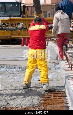 Group of construction workers spreading freshly poured concrete mix on the bridge Stock Photo