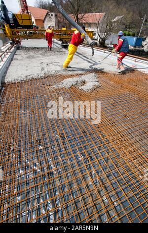 Group of construction workers spreading freshly poured concrete mix on the bridge Stock Photo
