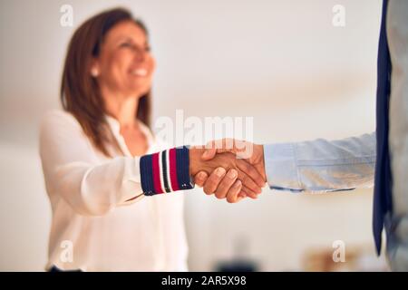 Two middle age business workers smiling happy and confident. Working together with smile on face doing handsake at the office Stock Photo