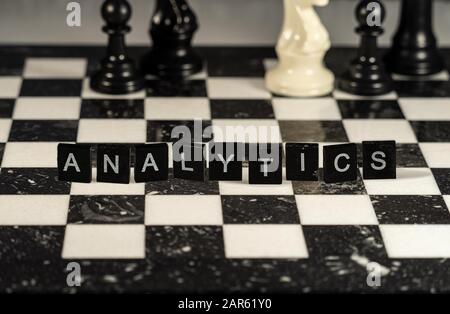 The concept of Analytics represented by black & white letter tiles on a chessboard Stock Photo