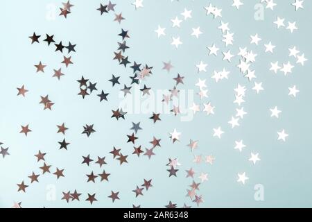 Star shaped silver sequins over blue background. Stock Photo
