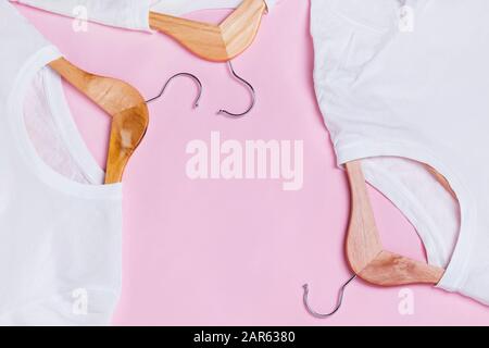 White T-Shirts on wooden hangers over pink background Stock Photo