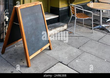 Empty blackboard table used for menus in front of restaurant on tiled stones pavement Stock Photo