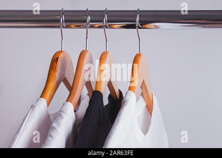 Row of white t-shirts on hangers on rack Stock Photo by FabrikaPhoto