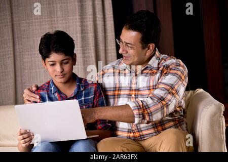 Father and son astonished on receiving good news using laptop Stock Photo