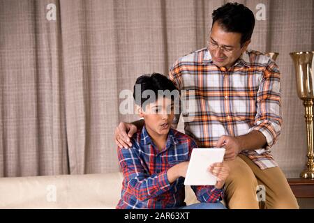 Father and son astonished on receiving good news using digital tablet Stock Photo