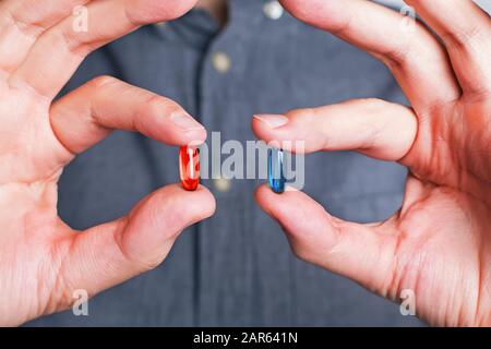 Man's hands close-up offering red and blue pills Stock Photo