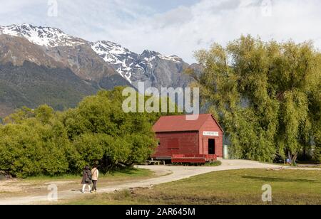 The red boat shed of Glenorchy, New Zealand in summer with two tourists in the distance