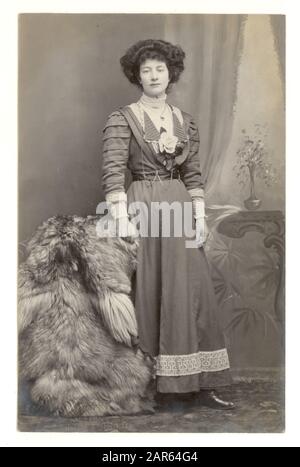 Early 1900's studio portrait postcard of beautiful wealthy looking Edwardian lady wearing a fashionable dress, furs as a prop, Knaresborough, North Yorkshire, England, U.K., circa 1910 Stock Photo