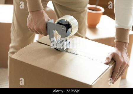 Close up of man packing box with adhesive tape Stock Photo