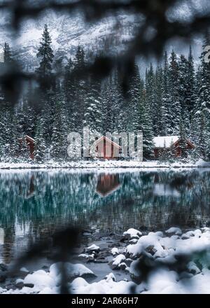 Wooden lodge in pine forest with heavy snow reflection on Lake O'hara at Yoho national park, Canada Stock Photo