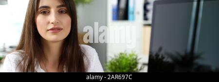 Pretty adult female sitting at worktable looking in camera Stock Photo
