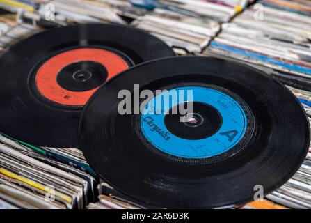 Two seven inch vinyl singles from the 1980s on top of a collection of  records Stock Photo