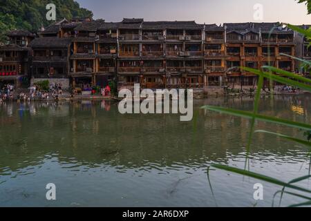 Fenghuang, China -  August 2019 : Old historic wooden Diaojiao houses on the riverbanks of Tuo river, flowing through the centre of Fenghuang Old Town Stock Photo