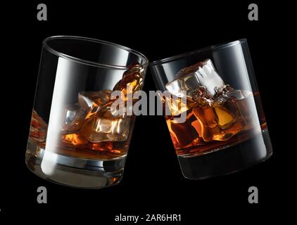 glasses of whiskey making toast with splashes on black background Stock Photo