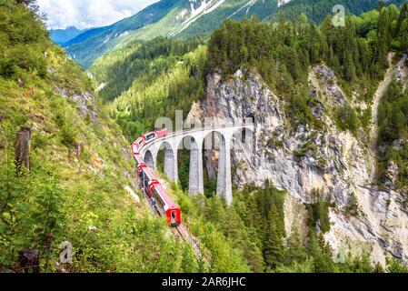 Landwasser Viaduct in Filisur, Switzerland. It is famous landmark of Swiss. Mountain landscape with red train of Bernina Express on high bridge. Sceni Stock Photo