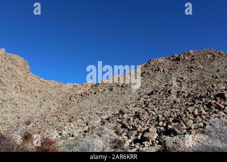 Below the deep blue Southern Mojave Desert sky rises ridges bounding Rattlesnake Canyon of Joshua Tree National Park. Stock Photo