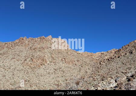 Below the deep blue Southern Mojave Desert sky rises ridges bounding Rattlesnake Canyon of Joshua Tree National Park. Stock Photo