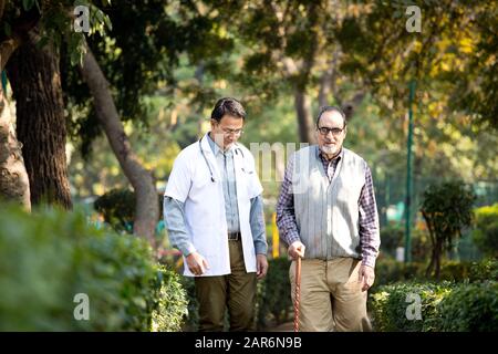 Doctor talking with senior man in hospital garden Stock Photo