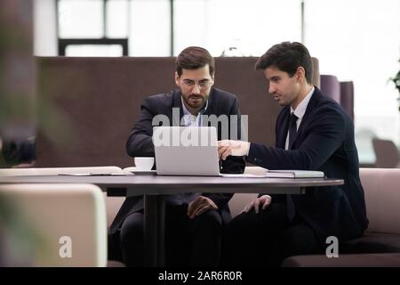 Focused employees in suits discussing corporate software. Stock Photo