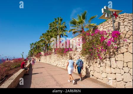 CANARY ISLAND TENERIFE, SPAIN - 27 DEC, 2019: Tourits walking on the boardwalk along Playa El Duque. It’ one of the most popular beaches on Tenerife. Stock Photo