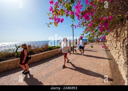 CANARY ISLAND TENERIFE, SPAIN - 27 DEC, 2019: Tourits walking on the boardwalk along Playa El Duque. It’ one of the most popular beaches on Tenerife. Stock Photo