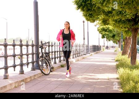 Full length shot of young woman running in the street in her morning run. Stock Photo