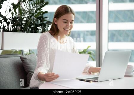 Happy young company employee holding documents, satisfied with report results. Stock Photo