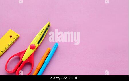 scissors, ruler and crayons on a pink background. Creative, fashionable, minimalistic, school or office workspace with yellow supplies for handycraft Stock Photo