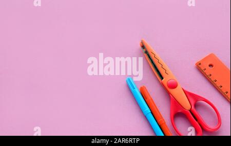 scissors, ruler and crayons on a pink background. Creative, fashionable, minimalistic, school or office workspace with orange supplies for handycraft Stock Photo