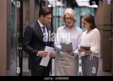Concentrated middle aged female leader showing project results to colleagues. Stock Photo
