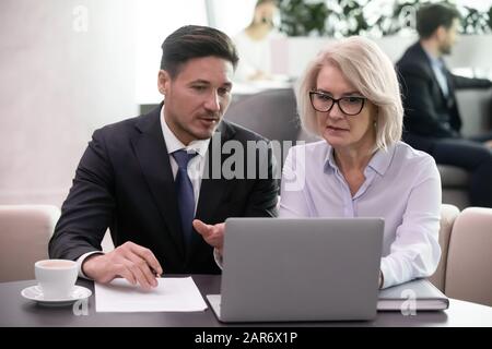 Focused businessman explaining financial results to middle aged female supervisor. Stock Photo